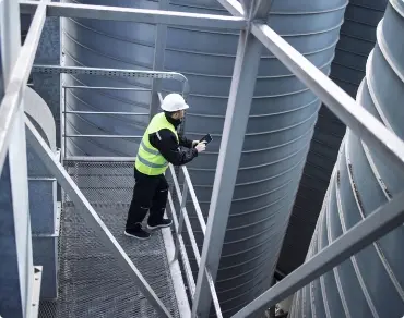 factory-silos-worker-standing-metal-platform-industrial-storage-tanks-looking-tablet-about-food-production